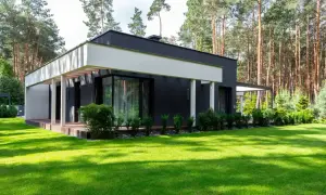 Nowoczesny dom z dużymi oknami i tarasem, otoczony zielonym ogrodem. Szacowany koszt budowy domu 220m2.