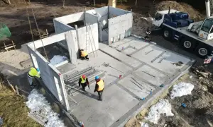 Budowa domu z keramzytu. Widać elementy prefabrykowane, dźwig i pracowników. Wady budowy mogą wynikać z pośpiechu.