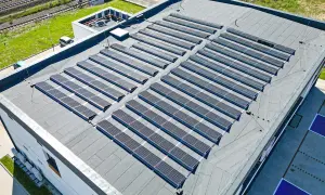 Duży dach płaski pokryty panelami fotowoltaicznymi, które zbierają energię słoneczną.