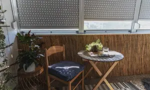 Przytulna loggia z drewnianym krzesłem, stolikiem i roślinami. Idealne miejsce na poranną kawę.