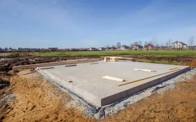 Budowa fundamentów cena: betonowa płyta na placu budowy, drewno przygotowane do dalszych prac.