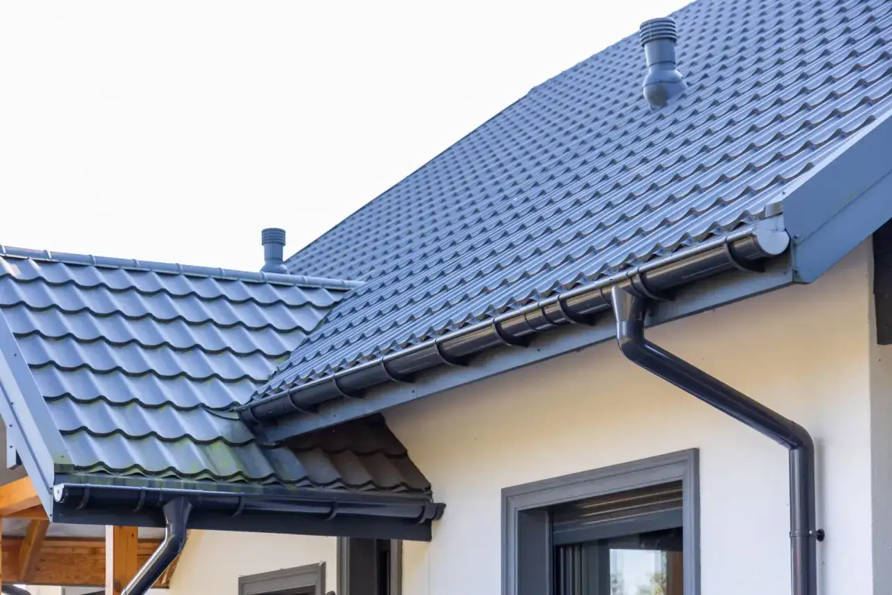 Szary dach z dachówki ceramicznej, rynny i komin. Sprawdź, jaka jest dachówka ceramiczna cena za m2.