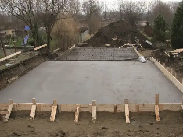 Plac budowy z wylana płytą betonową, przygotowywaną pod fundamenty. Widoczne zbrojenie i szalunki. Klasy ekspozycji betonu są kluczowe dla trwałości.