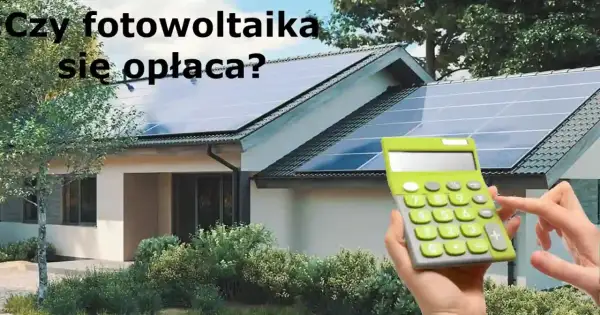 Dom z instalacją fotowoltaiczną na dachu. Kalkulator w dłoni sugeruje, że zastanawiamy się nad opłacalnością inwestycji.