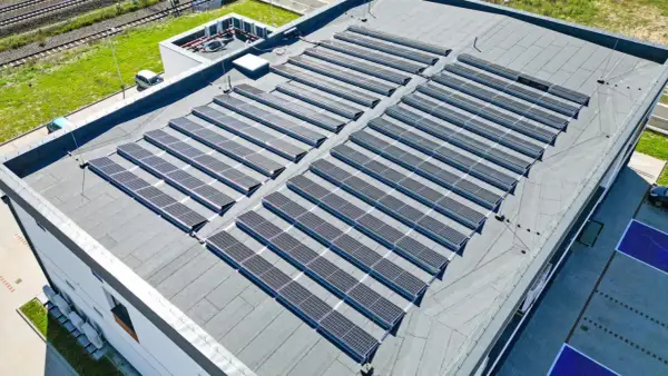 Duży dach płaski pokryty panelami fotowoltaicznymi, które zbierają energię słoneczną.