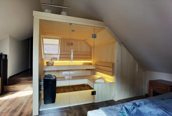 Nowoczesna sauna w domu, z przeszklonymi drzwiami i nastrojowym oświetleniem, idealna do relaksu.